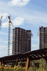 building cranes at front of a multi-storey uilding under construction, new house for many families, building