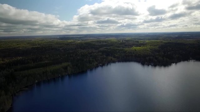 Aerial drone shot of lakes, forest and fields. Flying over Finland landscape. Reflection. Mirror surface lake water.