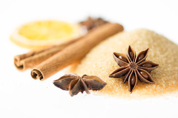 Selection of christmas spices with anise stars, cinamon sticks, brown sugar and dried orange ring isolated on white background