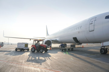 Passenger aircraft at the airport near the terminal. Unloading and loading baggage. Stock photo