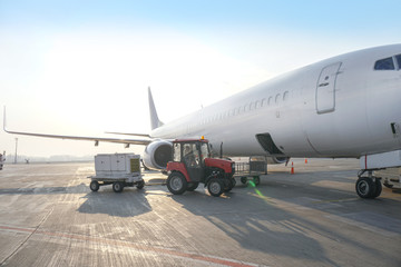 Passenger aircraft at the airport near the terminal. Unloading and loading baggage. Stock photo