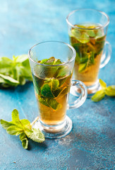 Cup of hot tea cane sugar dry tea leaves and mint herb.