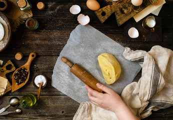 Overhead shot of homemade dough and rolling pin in woman hand