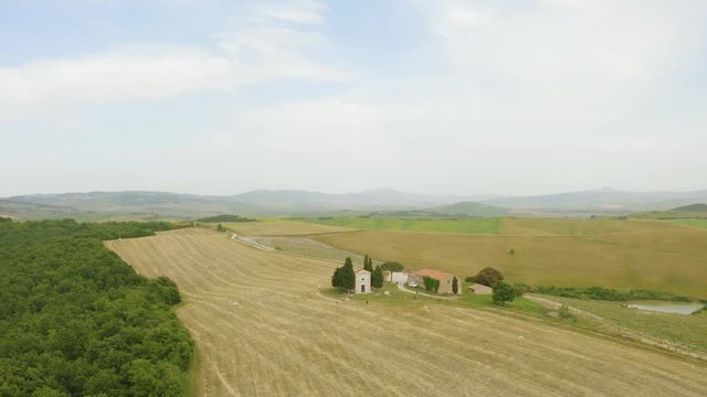 Chiesa Cappella della Madonna di Vitaleta piccola in mezzo a un campo di grano tra i cipressi.