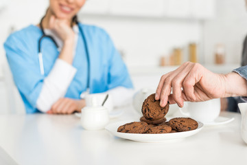 Selective focus of man hand with cookie and nurse on background