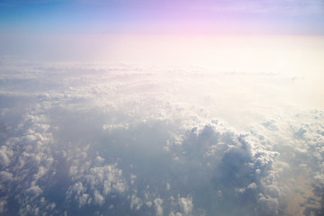 Naklejka na ściany i meble Airplane window overlooking the beautiful clouds and the earth. Sunset in flight on vacation. Tourist theme. Stock photo