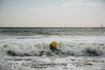 Buoy in the sea waves with foam. Empty beach. Summer vacations travel. Stormy ocean.