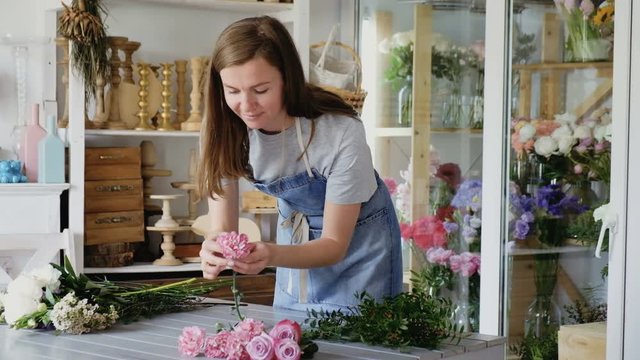 Beautiful young female florist makes a beautiful bouquet for sale in a shop. The concept of the female profession decorator and the scope of festive services