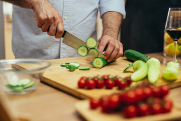 man cutting vegetables for salad in his kitchen