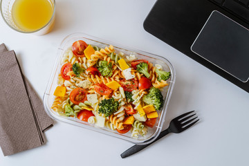 Healthy food in lunch box, on working table with laptop