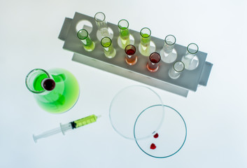 Erlenmeyer flask, Petri dish, Test tubes and a syringe with drops of blood inside is placed on...