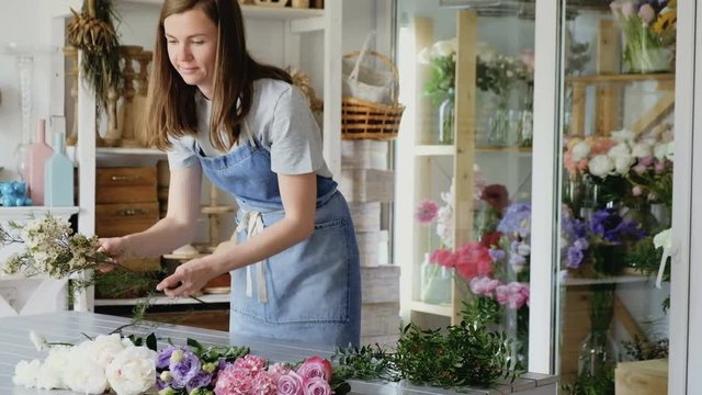 Charming young woman sorts beautiful flowers to create a magnificent bouquet in the workshop. Concept design holidays and weddings