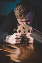 Young luthier working in his workshop, building a double bass