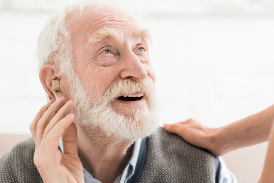 Glad man with hearing aid in ear, looking away