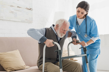 Arzt hilft Rentner beim Aufstehen vom Sofa