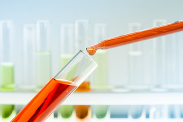 Pipettes bring blood samples to the test tube containing chemicals, close up, background