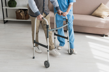 Senior man walking with nurse, and recovering from injury - obrazy, fototapety, plakaty