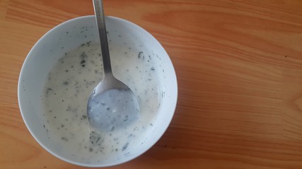 Close up of plain curd or yogurt or dahi in white ceramic bowl with silver spoon