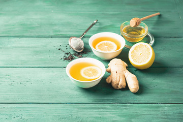 Tea lemon ginger with honey in a white cup on a wooden rustic background. Healthy drink for detox...