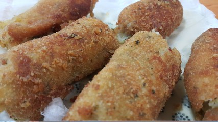 Spicy and delicious croquettes served in ceramic plate over wooden floor