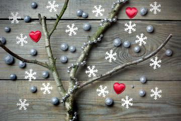 Original christmas tree concept with leafless branch, silver brocade pellets, silver bead chain, red hearts and snow flakes on wooden boards
