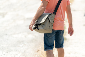 a man in a peach t-shirt with a bag over his shoulder