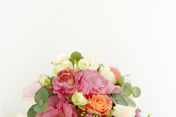 wedding rings on the bouquet with flowers roses on a white background with copy space. minimal concept. mockup