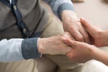 Cropped view of woman holding hands with senior man