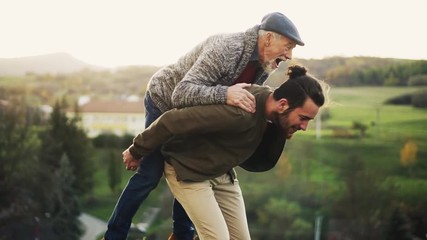 Senior father and his son walking in nature, having fun. Slow motion. - Powered by Adobe