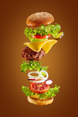 Big tasty home made burger with flying ingredients on white background. Isolated.