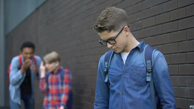 Teenagers mocking boy in eyeglasses, spreading malicious rumors, verbal bullying