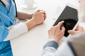 Cropped view of hands pointing at digital tablet with blank screen
