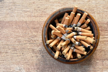 cigarette filter in ceramic ashtray on wooden background