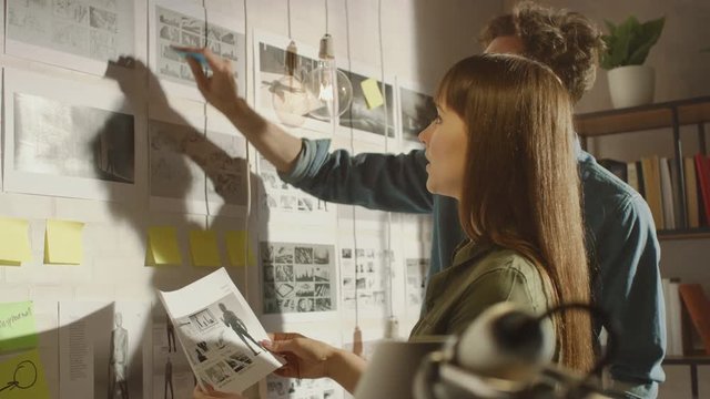 Young Creative Male and Female are Organizing a Mood Board on a Wall of Their Cool Office Loft. Pictures Represent Future Motion Video. Colleagues are Working and Discussing the Project. Sunny Day.