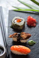 Top view traditional japanese sashimi sushi with soy sauce wasabi and ginger with chops ticks on black board background