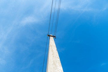 A pole with wires going out horizontally against a bright blue sky. Image has copy space. photo view from below