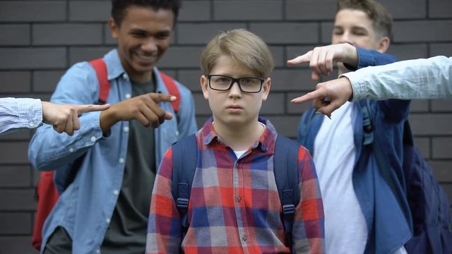 Bullied boy looking at camera, depressed by classmates mockery, verbal abuse