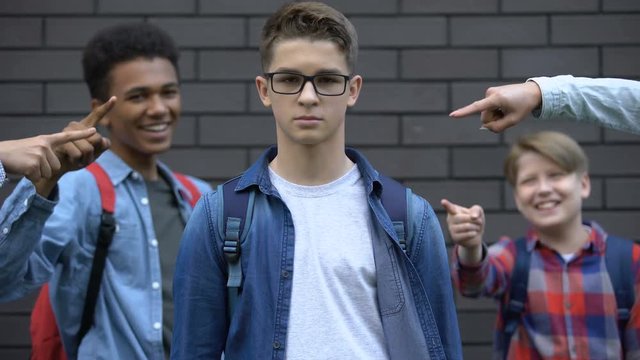 Boy boldly looking into camera despite mockery of classmates, resisting bullying