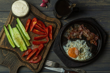Breakfast-scrambled eggs, garlic sauce, tomatoes, cucumbers, bacon and coffee. Top view