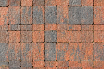 The surface is paved with road tiles of different sizes (multi format). The uneven color of the tile makes it look like a natural stone. View from above.