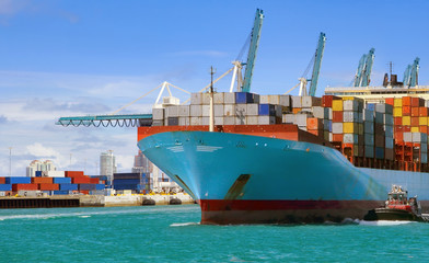 Large cargo ship with many shipping containers sailing from port 