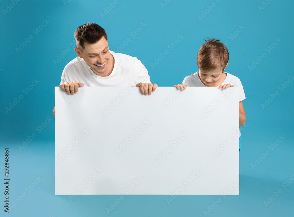 Wall mural dad and his son with empty banner on color background. space for design