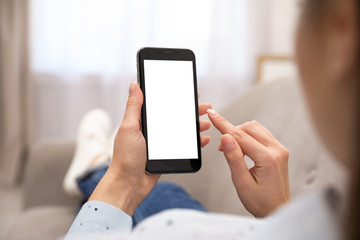 Woman holding smartphone with blank screen indoors, closeup of hands. Space for text