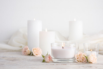 Composition with burning aromatic candles and roses on wooden table. Space for text