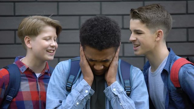 Teen bullies teasing african american boy, calling names or insulting, racism