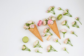 in two wafer cones are pink roses and macaroons, around are pink roses