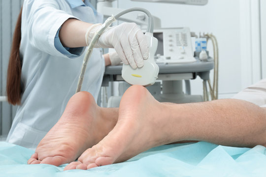 Doctor conducting ultrasound examination of patient's foot in clinic