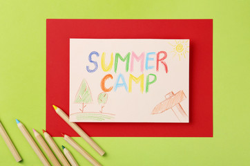 Paper with written text SUMMER CAMP, drawings and different pencils on color background, flat lay