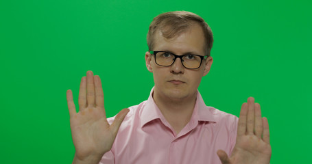 Handsome young man in shirt saying no and doing stop gesture with a hand