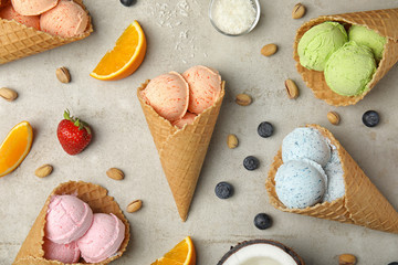 Fototapeta na wymiar Flat lay composition with delicious ice creams in waffle cones on table